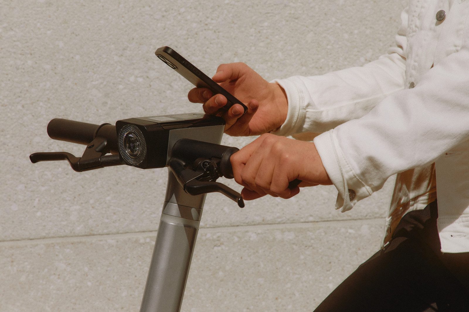 A rider checking a phone on a scooter